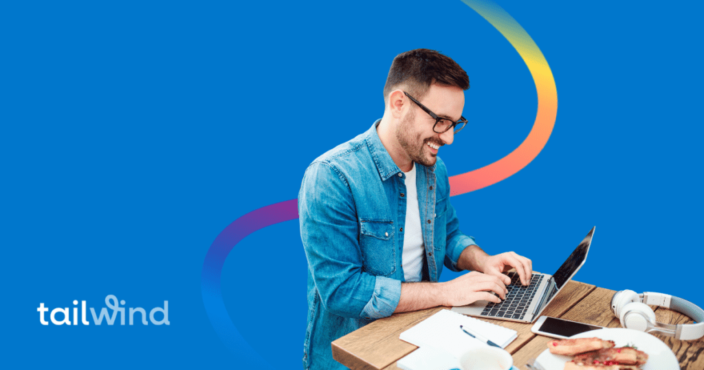 Man sitting at a desk working on a lapotp against a blue background with the Tailwind logo.