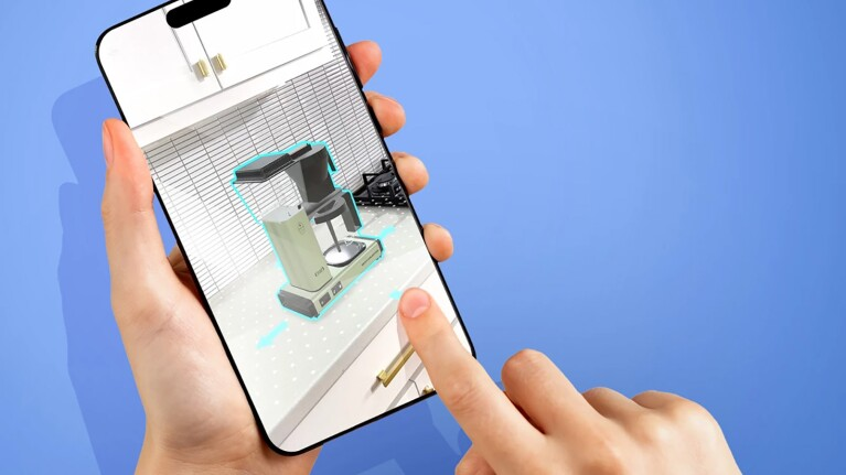 Screenshot of person holding a smartphone showing them using AR to "view" a coffee maker on their kitchen counter.